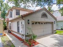 Two-story home with a two car garage, red tile roof, and manicured landscaping at 995 Troon Trce, Winter Springs, FL 32708