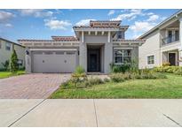 Charming home with a brick driveway, two-car garage and well-manicured lawn under a sunny blue sky at 13556 Abberwick Dr, Orlando, FL 32832