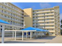 Harborview building with balconies and covered parking with blue canvas, set against a clear blue sky at 145 N Halifax Ave # 705, Daytona Beach, FL 32118
