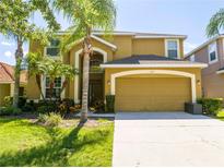 Charming two-story home featuring a well-manicured lawn, mature palm trees, and an attached two-car garage at 2515 Dharma Cir, Kissimmee, FL 34746