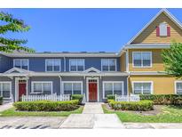 Charming townhome featuring a red front door, white picket fence, and well-manicured landscaping at 2605 Gala S Rd # 106, Kissimmee, FL 34746