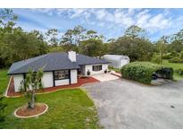 Charming single story home boasts mature landscaping, black accents, and a long gravel driveway at 2630 S Tanner Rd, Orlando, FL 32820