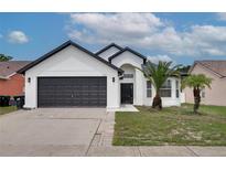 Beautiful home featuring a dark garage door, well-manicured lawn, and healthy palm trees for added curb appeal at 2639 Monaco Cove Cir, Orlando, FL 32825