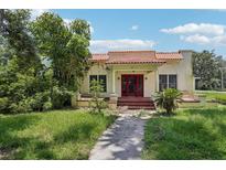 Charming home featuring a red-tiled roof, red front doors, and mature landscaping at 302 E Oakland Ave, Oakland, FL 34760