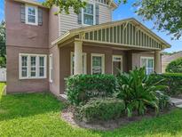 Charming two-story home featuring a covered porch with stately columns and lush, manicured landscaping at 6971 Tettenhall Ln, Windermere, FL 34786