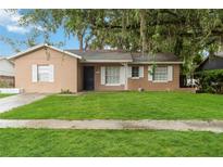 Charming single-story home with a well-manicured lawn and mature trees adding curb appeal at 8111 Esperanza St, Orlando, FL 32817