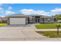 Charming single-story home featuring a gray exterior, well-manicured lawn, and an attached two-car garage at 906 Highland Crest Cir, Lake Wales, FL 33853
