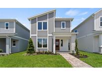 Modern two-story home with gray siding, stone accents, red door, and manicured lawn at 2046 Education St, St Cloud, FL 34771