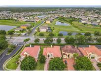 Stunning aerial view of a residential area with multiple homes, a pond, and lush green spaces at 2209 Callaway Ct, Davenport, FL 33837
