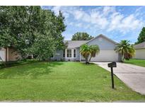 Charming single-story home with a well-manicured lawn, palm trees, and a two-car garage at 253 Churchill Ct, Kissimmee, FL 34758