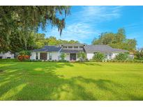Stunning ranch-style home featuring a manicured lawn, a white brick facade, and mature landscaping at 3160 Whisper Wind Dr, St Cloud, FL 34771