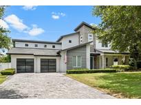 Contemporary home featuring a stone facade, three-car garage, and a well-manicured lawn at 617 Worthington Dr, Winter Park, FL 32789