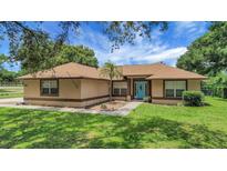 Inviting single-story home with a landscaped front yard and blue front door, exuding curb appeal at 10697 Lake Hill Dr, Clermont, FL 34711