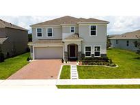 Charming two-story home features a brick driveway, two-car garage, and a well-manicured lawn at 1588 Sky Lakes Dr, St Cloud, FL 34769