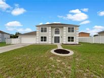 Two-story home featuring a front yard with green grass, complemented by a two-car garage and white fence at 1793 Western Hills Ln # N, Mascotte, FL 34753