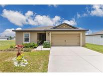 Charming single-story home showcasing a well-manicured lawn and welcoming two-car garage at 205 Cimarron Dr, Kissimmee, FL 34759