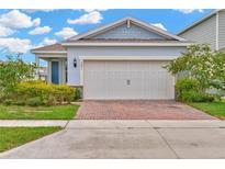 Charming single-story home with a brick driveway and attached two-car garage at 2601 Blowing Breeze Ave, Kissimmee, FL 34744