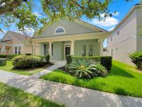 Charming home featuring a manicured lawn and inviting front porch with decorative columns at 2679 Rainbow Springs Ln, Orlando, FL 32828