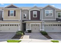 Charming townhome featuring a two-car garage, brick driveway, and beautifully landscaped front yard at 4733 Cliveden Loop, Sanford, FL 32773