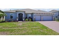 Charming single-story home featuring a well-manicured lawn, brick driveway, and a two-car garage at 5264 Obsidian Gate Dr, Mount Dora, FL 32757