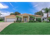 Inviting single-story home with manicured lawn, mature palms, and a paver driveway leading to the attached three-car garage at 800 Sterling Chase Dr, Port Orange, FL 32128