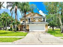 Inviting tan two-story home with a two-car garage, mature landscaping, and blue skies at 1212 Bradwell Dr, Orlando, FL 32837