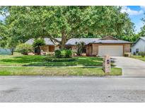 Charming brick home featuring a mature tree, well-manicured lawn, and inviting curb appeal at 1343 S Ridge Lake Cir, Longwood, FL 32750