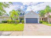 Charming two-story home featuring lush landscaping, palm trees, and a welcoming brick driveway at 1639 Balsam Willow Trl, Orlando, FL 32825