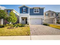 Charming two-story home featuring a two-car garage, a brick driveway, and a manicured lawn with shrubs at 2354 Emerald Springs Dr, Apopka, FL 32712