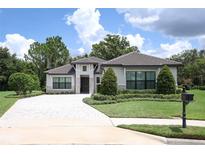 Charming single-story home with manicured lawn, neatly trimmed hedges, and a stone-paved driveway at 25974 High Hampton Cir, Sorrento, FL 32776