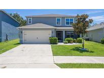 Charming two-story home with manicured lawn, a two-car garage, and beautiful landscaping at 3759 Crimson Clover Dr, Mount Dora, FL 32757