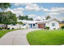 Charming single-story home with a well-manicured lawn, circular driveway, and modern exterior paint at 402 Saint Dunstan Way, Winter Park, FL 32792