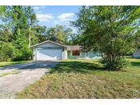 Charming single-story home featuring a large front yard, driveway, and attached garage at 468 E Oakwood Ave, Orange City, FL 32763