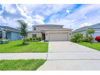 Two-story home with beige exterior, green lawn, and a two car garage at 5345 Tuscany Ln, Davenport, FL 33897