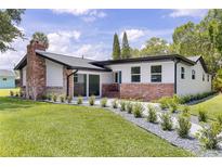 Charming home featuring a brick chimney, complemented by a lush green lawn and modern landscaping at 608 Cedar Ave, Holly Hill, FL 32117