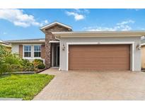 Charming single-story home featuring a stone accent wall and a two-car garage at 911 Tidal Pond Dr, Groveland, FL 34736