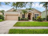 Inviting home featuring a manicured lawn, two car garage, and lush landscaping at 9650 Bay Pine Ln, Orlando, FL 32832