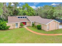 Stunning home featuring a well-manicured lawn, mature trees and an inviting red door at 1102 Winter Springs Blvd, Winter Springs, FL 32708