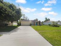 Charming one-story home featuring a manicured lawn, long driveway and a welcoming turquoise front door at 1877 Courtland Blvd, Deltona, FL 32738