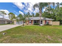 Charming single-story home with mature trees, solar panels, awnings, and a spacious front lawn at 37 Pecan Pass Trl, Ocala, FL 34472