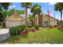Charming home featuring a manicured lawn, palm trees, and vibrant landscaping at 5704 Bay Side Dr, Orlando, FL 32819