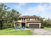 Charming two-story home with a well-manicured lawn and a cozy seating area with blue rocking chairs at 6346 Dallas Blvd, Orlando, FL 32833