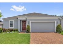 Charming home featuring a two-car garage, manicured lawn, and inviting brick-paved driveway at 1156 Cavender Creek Rd, Minneola, FL 34715