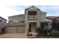 Two-story home featuring neutral stucco, a two-car garage, brick driveway, and a small balcony at 11837 Cave Run Ave, Windermere, FL 34786