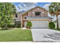 Charming two-story home with a manicured lawn, complemented by lush landscaping and a spacious two-car garage at 14332 Grassy Cove Cir, Orlando, FL 32824