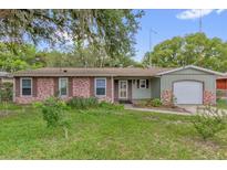 Charming single-story home featuring a brick facade, green siding, and a well-maintained front yard at 14402 Sw 34Th Terrace Rd, Ocala, FL 34473
