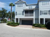 Well-maintained townhome featuring a two-car garage, a charming porch, and lush landscaping at 2406 Grand Central Pkwy # 14, Orlando, FL 32839