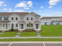 Charming two-story townhome with well-manicured lawn and inviting entryway, under a bright sky at 3231 Gardenia Reserve St, Apopka, FL 32712