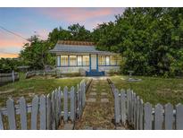 Charming single-story home with blue trim, a quaint picket fence, and lush surrounding trees at 516 Tybee Pl, Orlando, FL 32829