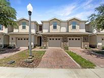 Charming townhouses with brick driveways and attached garages under a beautiful blue sky at 576 Prospect Pt, Oviedo, FL 32765